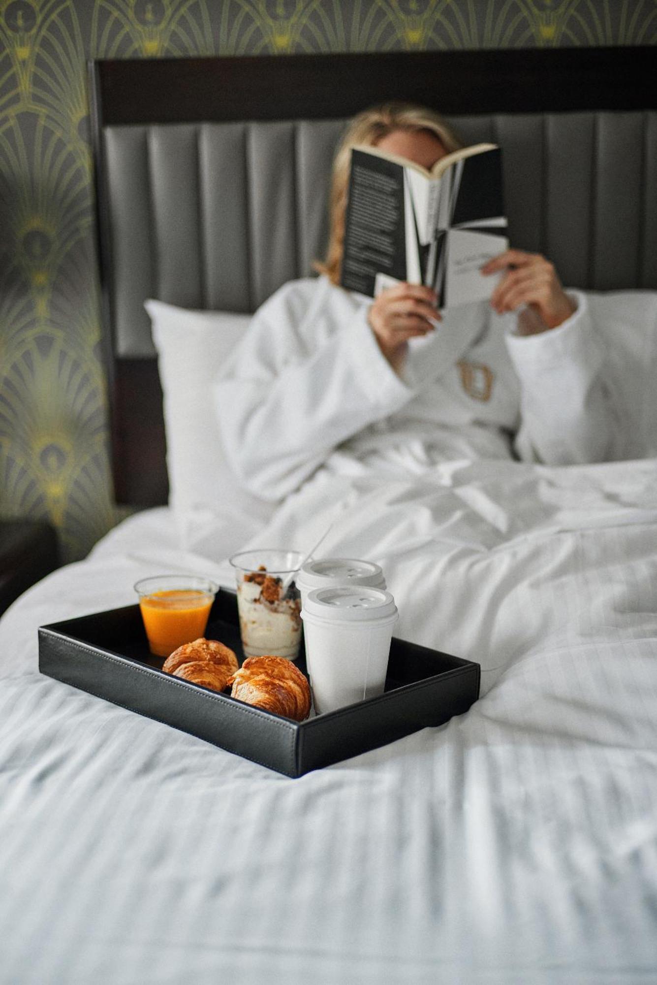Hotel Edison Times Square New York Esterno foto A woman reading a book while lying in bed.